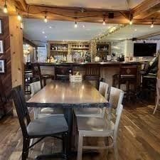 Inside Blackbird Cafe — communal wooden tables, a pressed-tin ceiling, and the bar visible at the back beneath rows of hanging pendant lights.