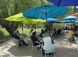The Blackbird Cafe patio — wrought-iron tables under string lights with the creek just beyond.