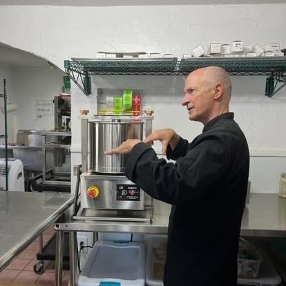 The chocolatier behind Blue Spruce Chocolates in his black chef’s coat, hand-finishing a tray of dark-chocolate truffles in the Kittredge kitchen.