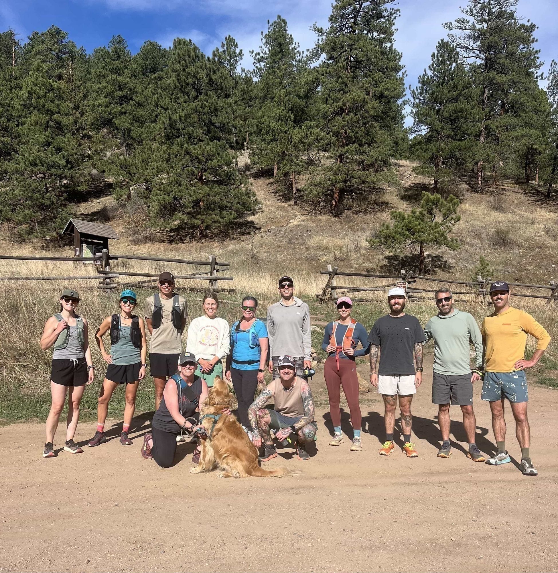 Members of the Kittredge Run Club gathered together at Bear Creek Park, smiling for a group photo with their dog.