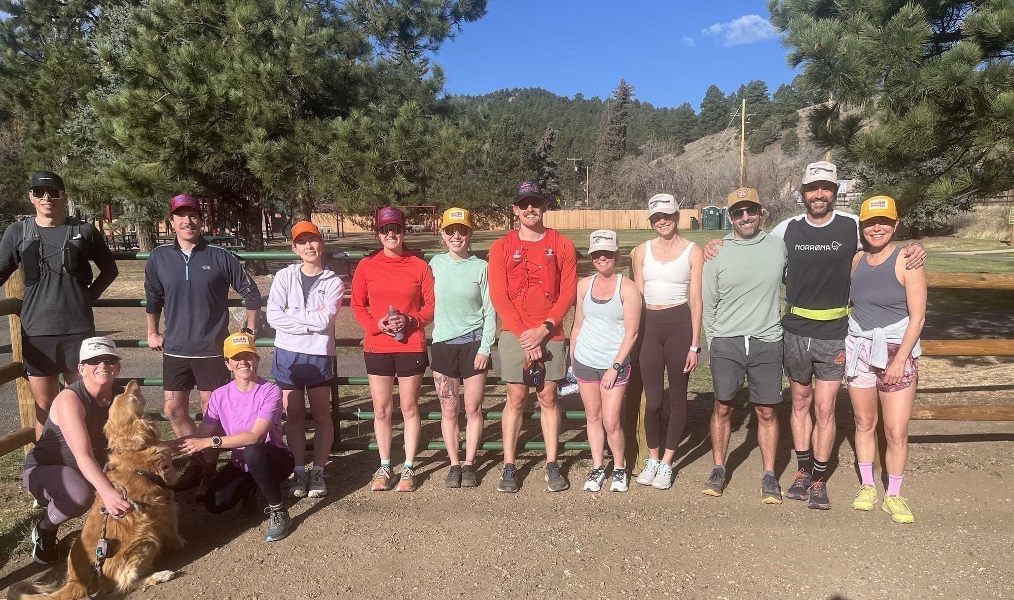 The Kittredge Run Club posing at a Bear Creek trailhead with a golden retriever in the foreground.