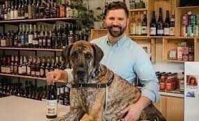 A friendly customer and his dog hanging out near the front of Piney Wine & Spirits, waiting for the next neighbor to come in.