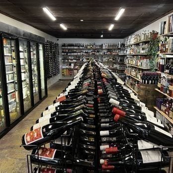 A close-up of a single shelf at Piney Wine & Spirits — Colorado wines and small-batch spirits stood up in a tidy row.